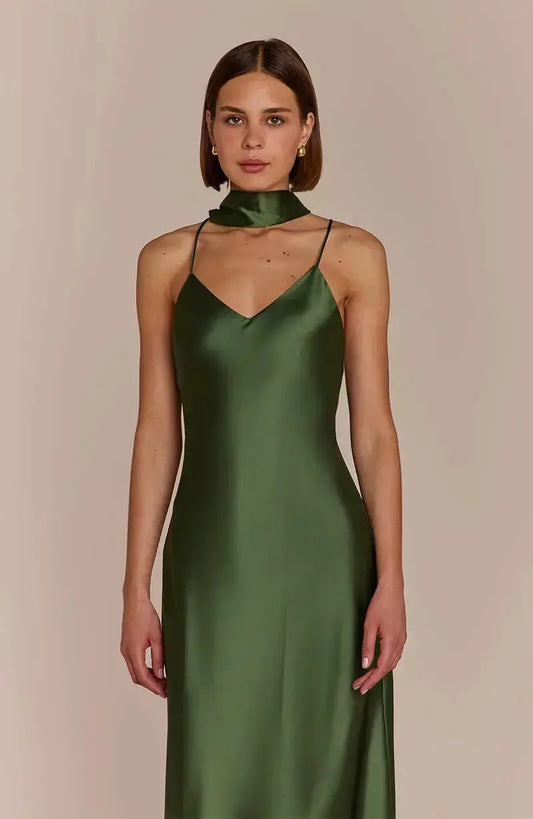 Woman wearing a olive green satin bridesmaid dress against a beige background