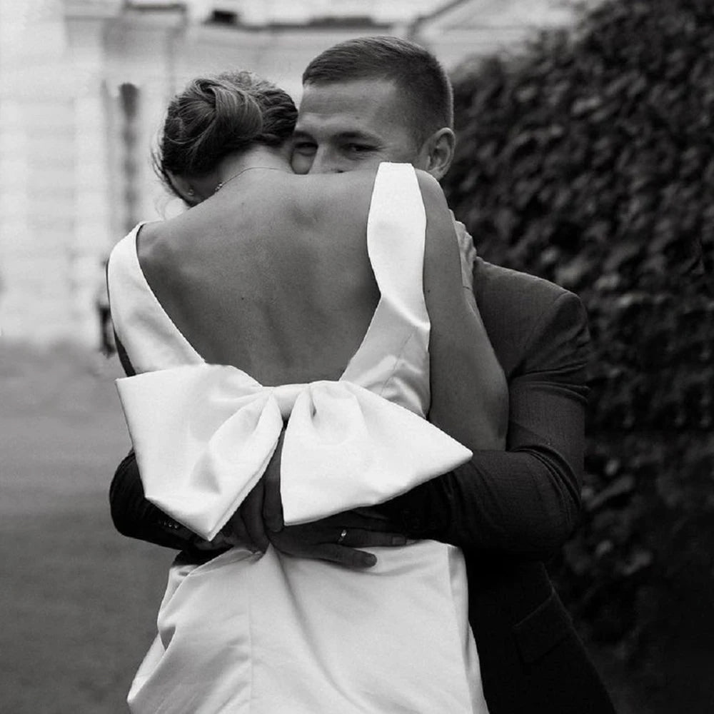 groom lifting bride wearing a Short Boho V-Neck Wedding Dress with a Large Bow and Detachable Train
