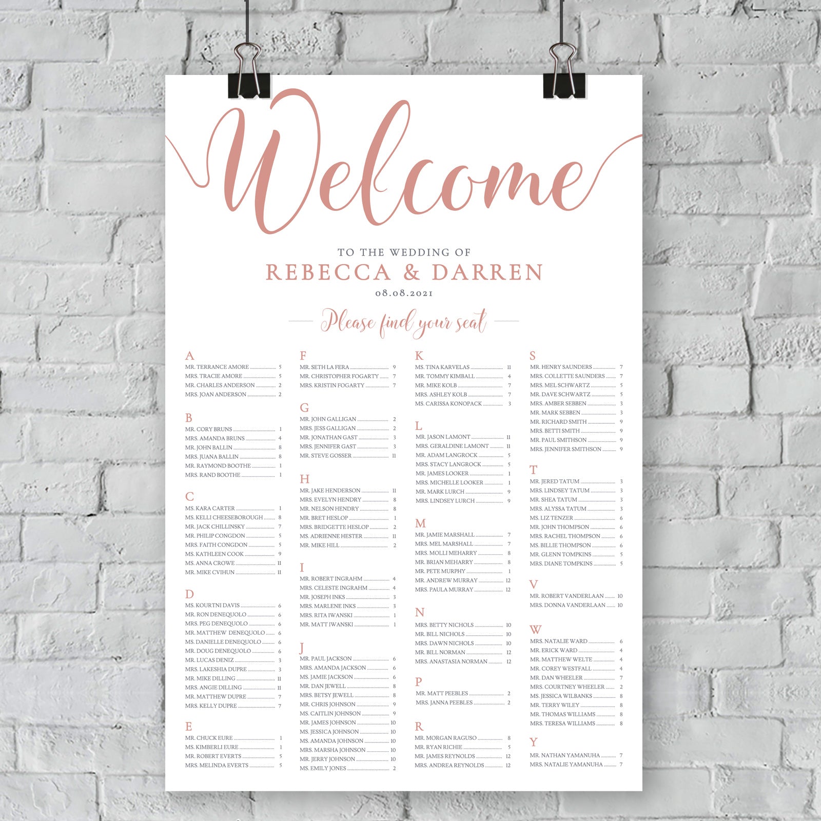 rose gold seating chart on a brick wall