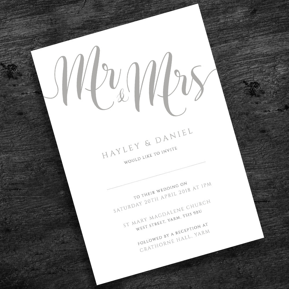 silver wedding invitation on wooden table