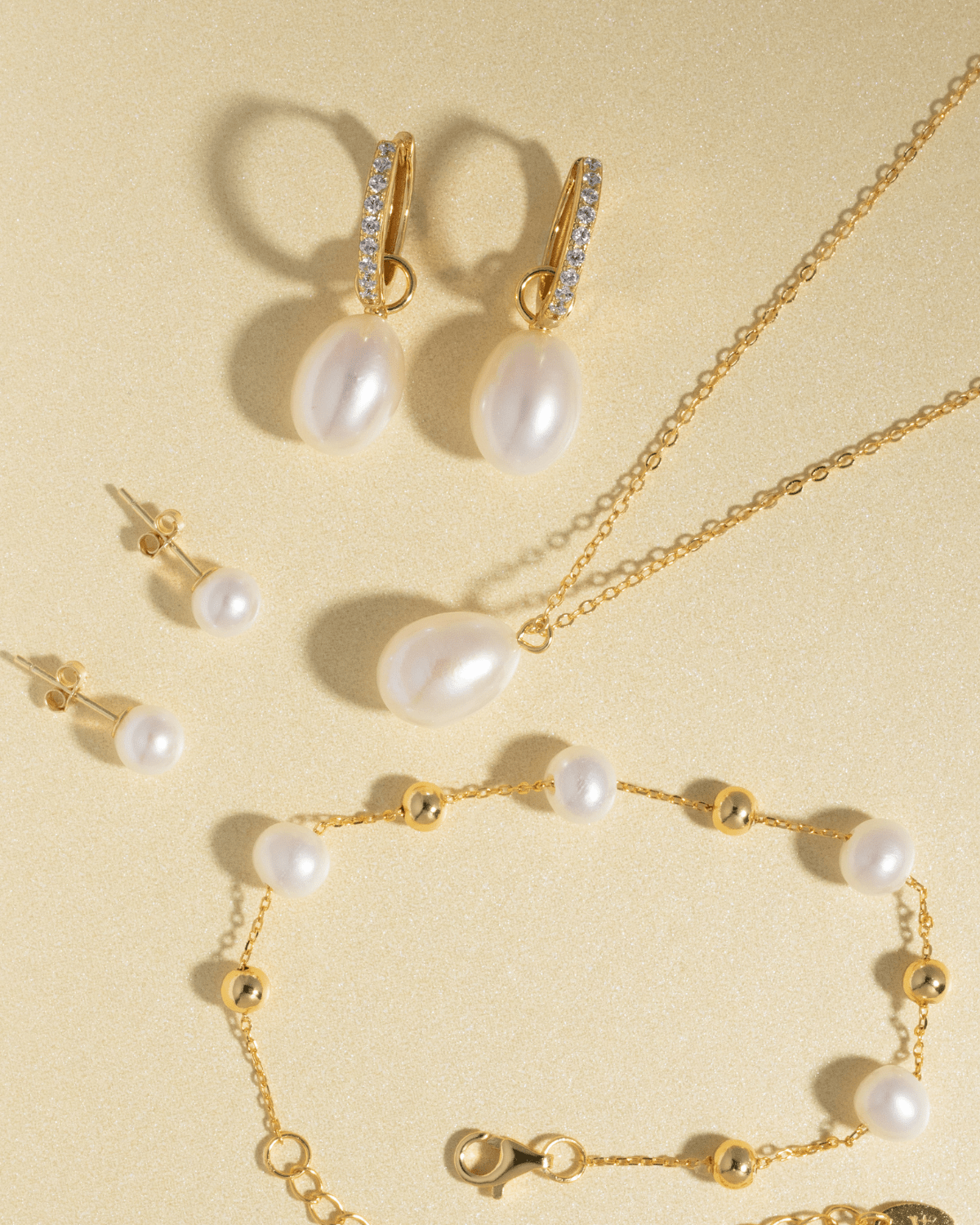 A complete pearl jewelry set including a necklace, hoop earrings, stud earrings, and bracelet.