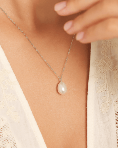 A model wearing a white pearl pendant necklace.