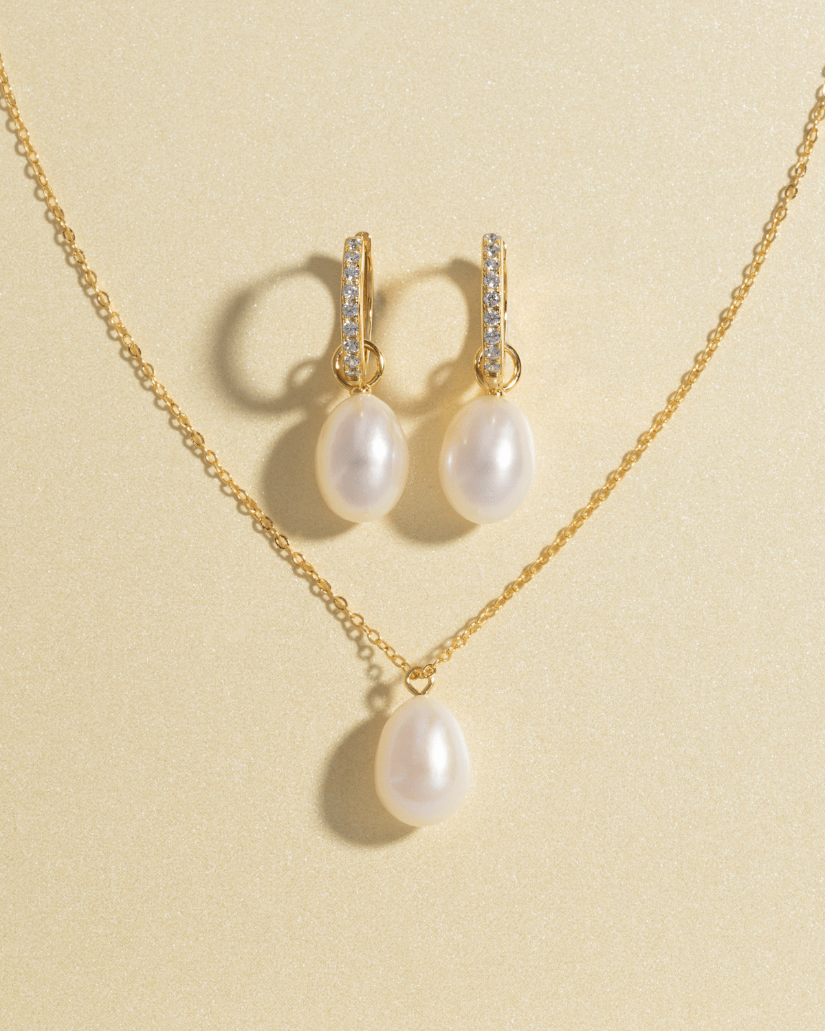 A gold pearl pendant necklace and matching gold pearl drop earrings.