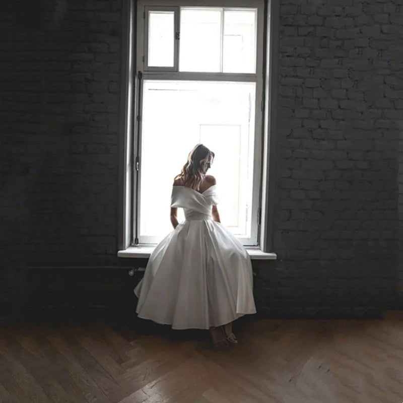 Bride in A-Line Ankle-Length Off-The-Shoulder Wedding Dress sat on a window ledge