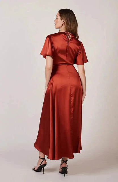 Woman wearing a rust-colored burnt orange satin bridesmaid dress against a plain background