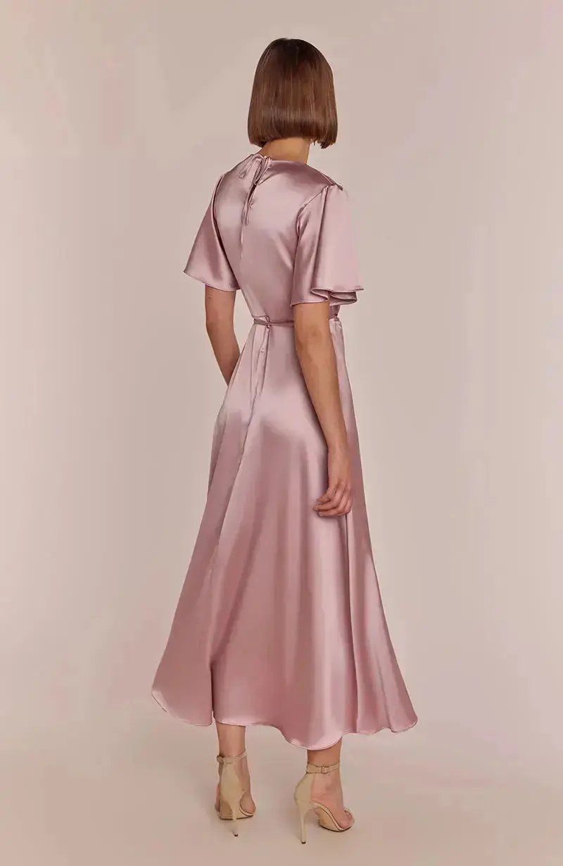 Woman wearing a rose pink satin bridesmaid dress against a plain background