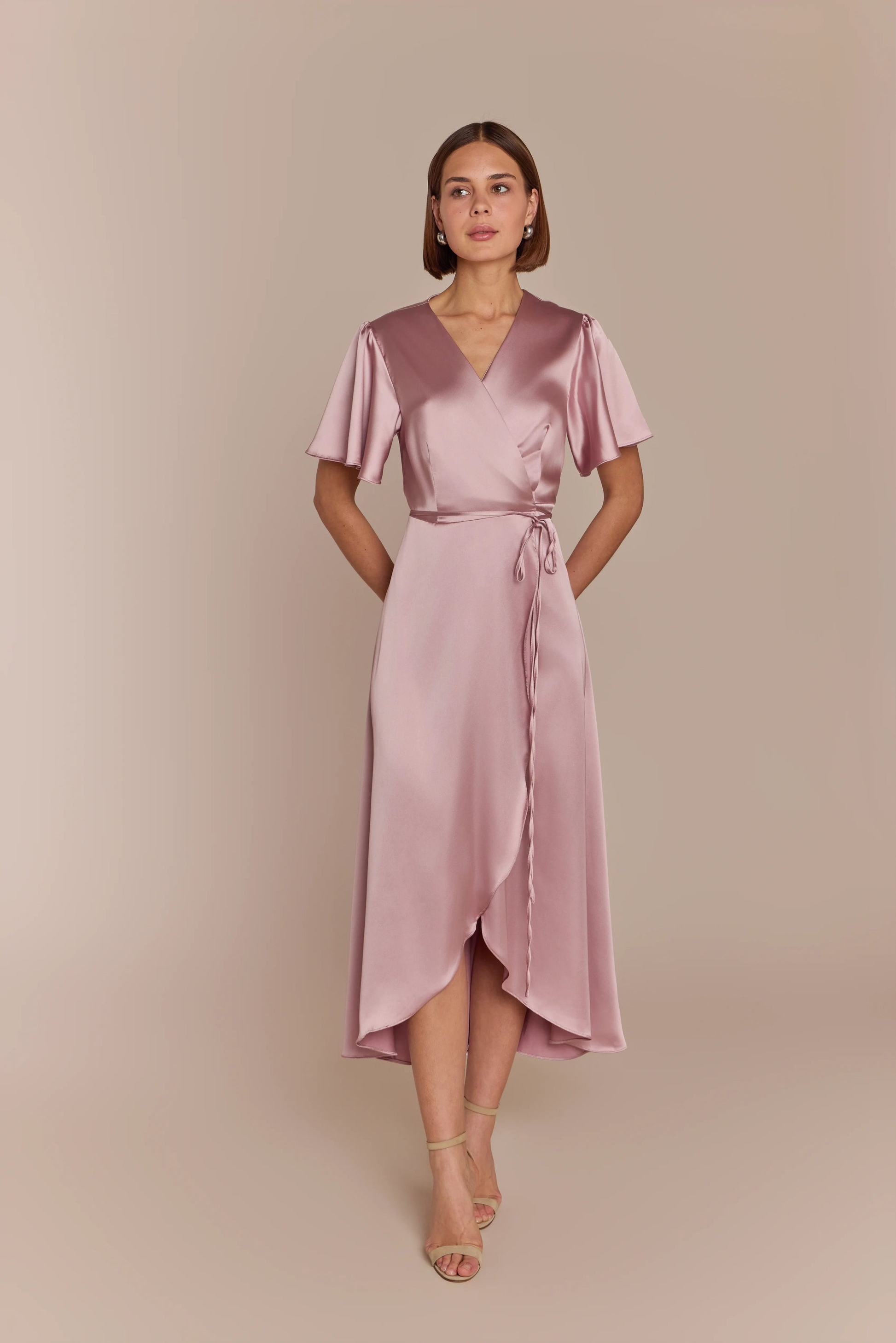 Bridesmaid wearing a pink satin dress against a beige background