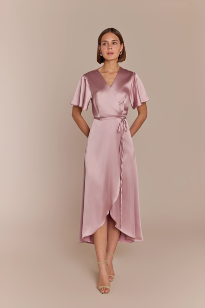 Bridesmaid wearing a pink satin dress against a beige background