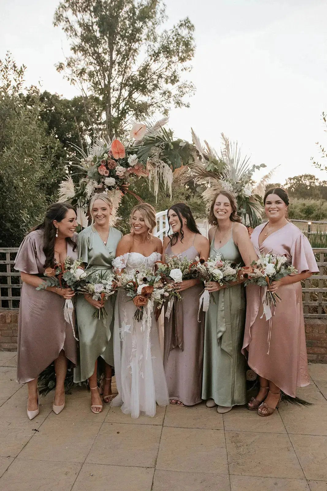 bride and bridesmaids in colorful dresses holding bouquets outdoors