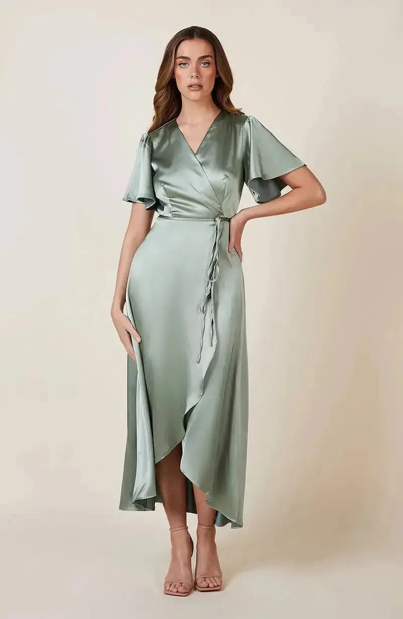 Bridesmaid wearing a sage green satin wrap dress against a beige background