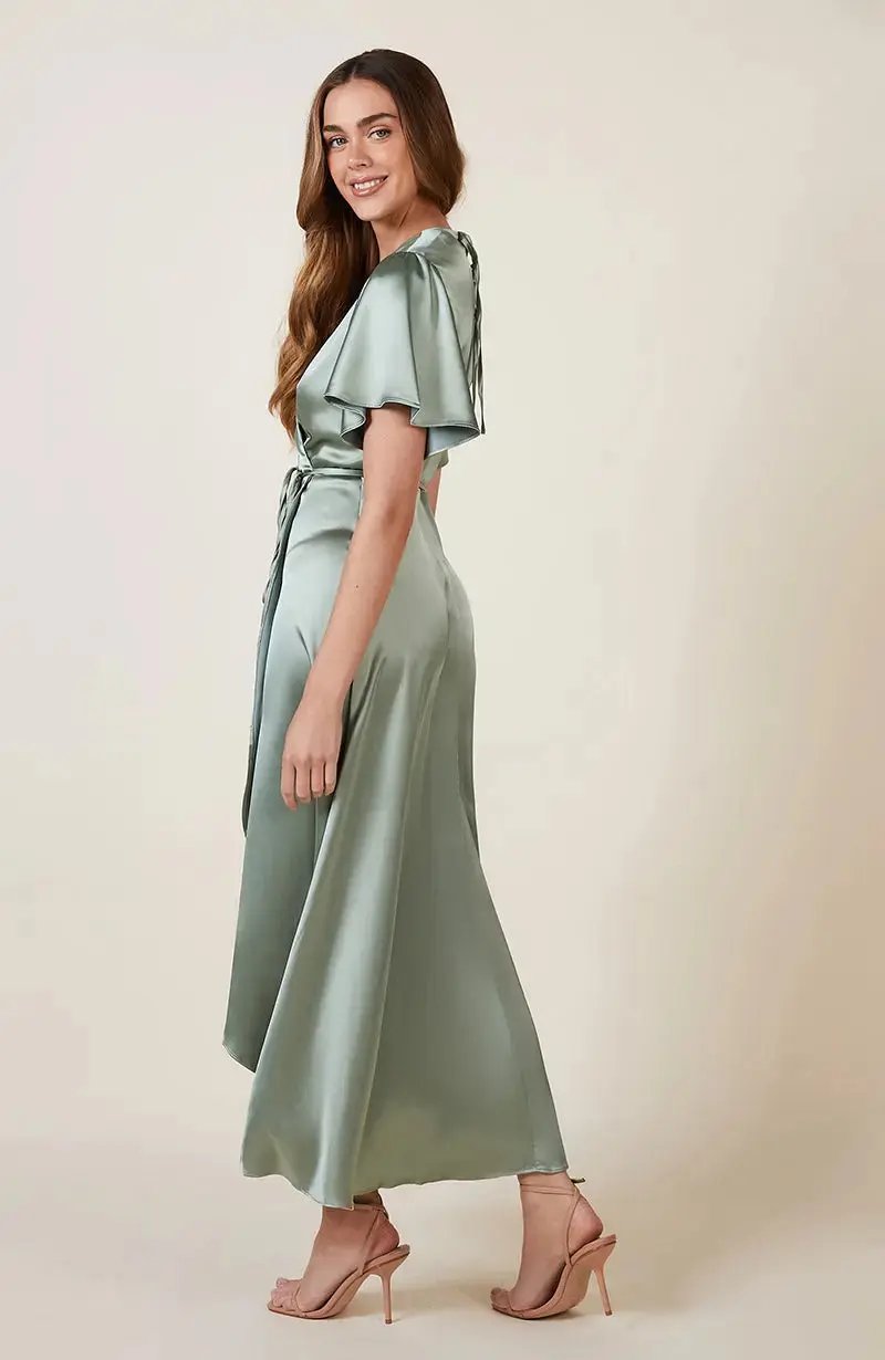 Woman wearing a light sage green Bridesmaid dress with a belt on a beige background