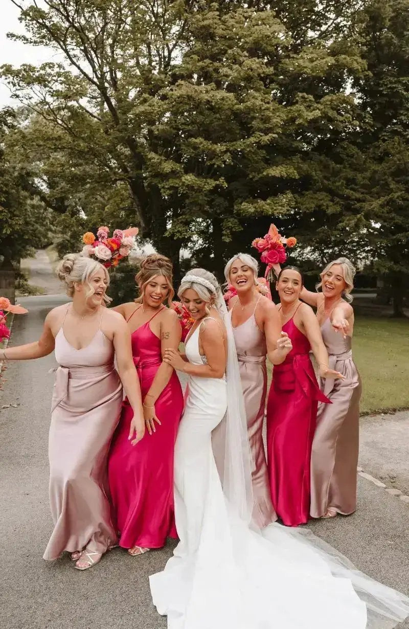 Bride with bridesmaids in pink and red dresses standing outdoors.