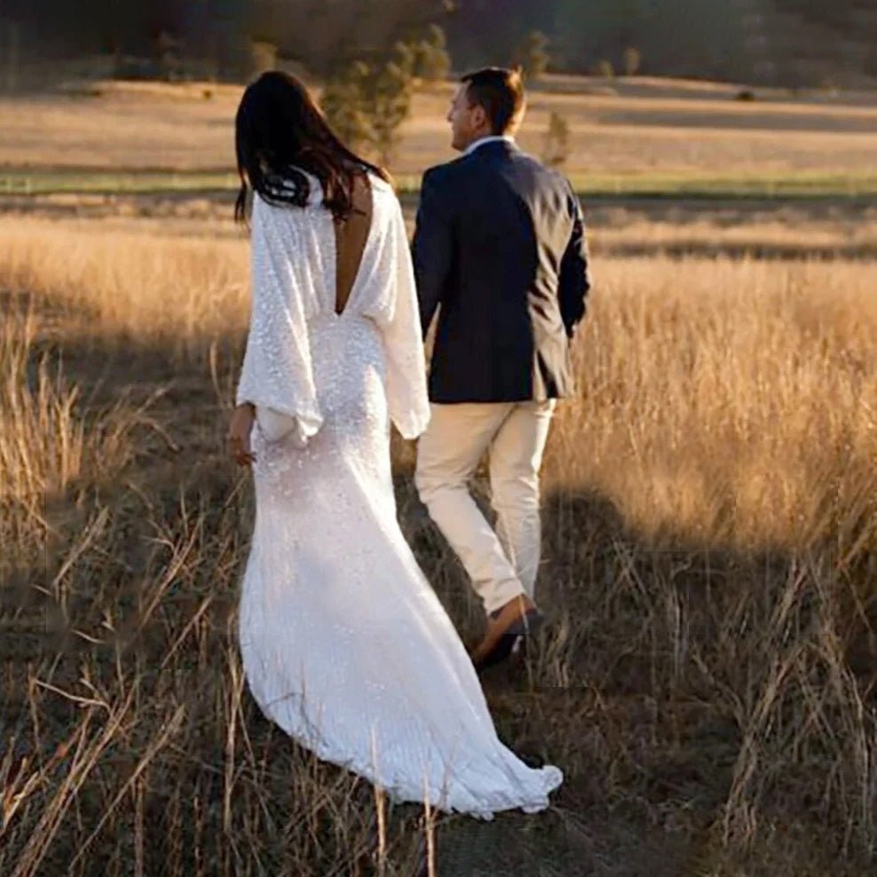 Rear-view of Bride wearing Luxury Long Sheer Sleeve Deep Backless Wedding Dress with groom in a field