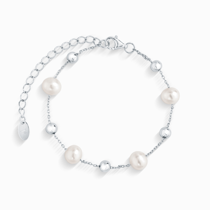 A close-up of a silver chain bracelet with five evenly spaced white pearls and silver beads.