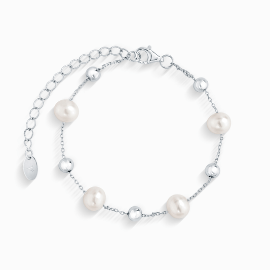 A close-up of a silver chain bracelet with five evenly spaced white pearls and silver beads.