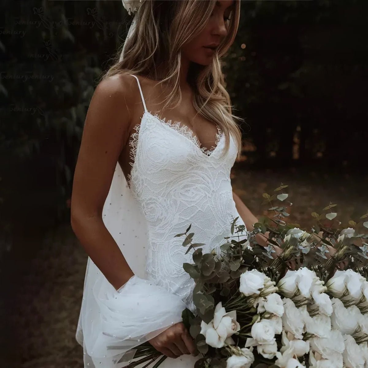 Bride in Sexy Backless Lace Boho Mermaid Wedding Dress holding flowers