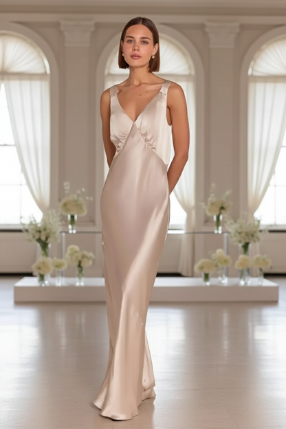 Bridesmaid in a champagne satin Bridesmaid gown standing in a room with large windows and floral arrangements.