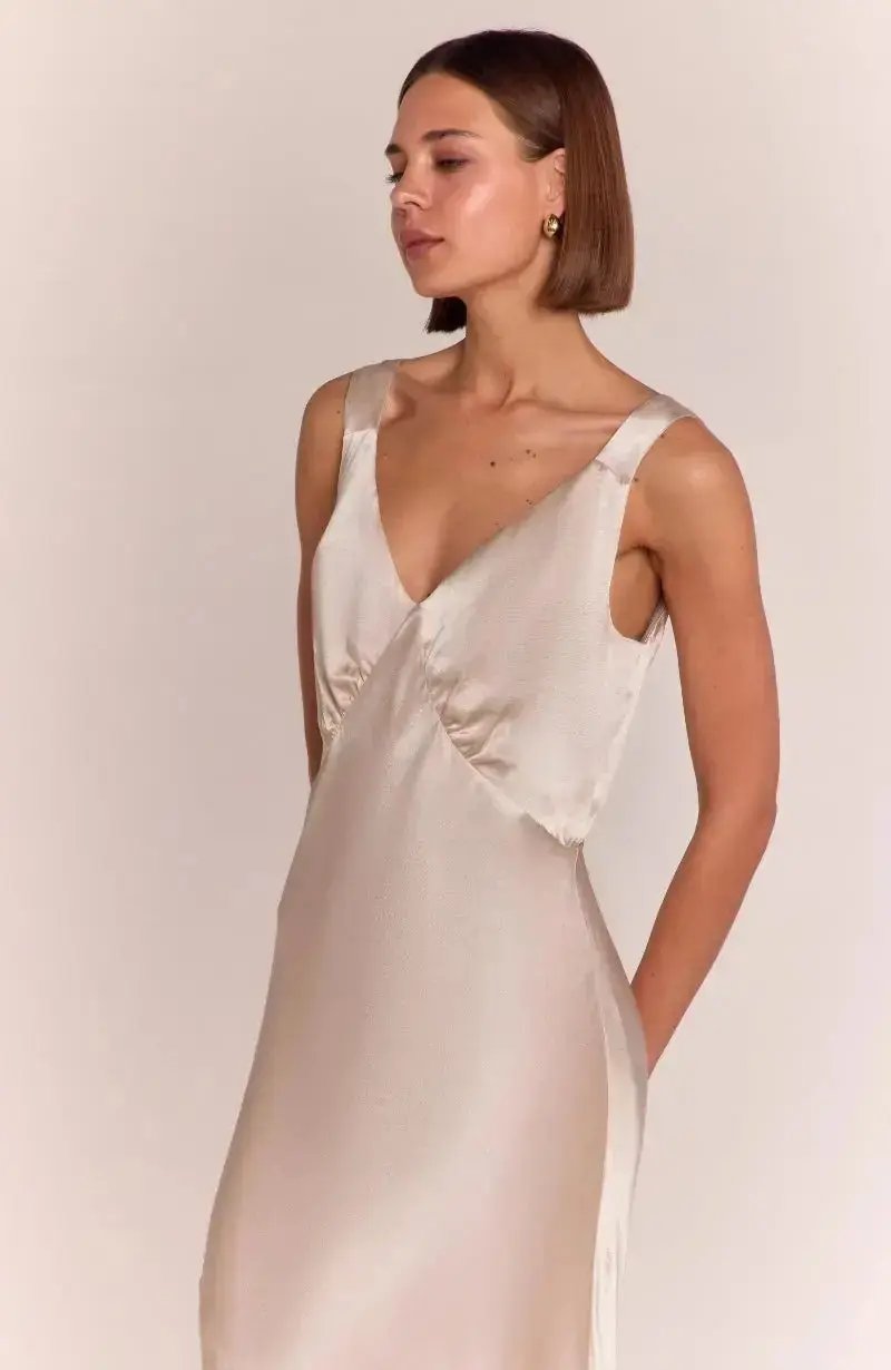Bridesmaid wearing a champagne satin slip dress against a plain background
