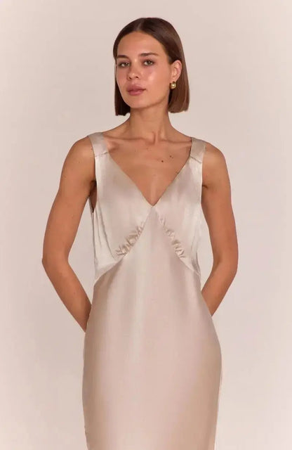 Bridesmaid wearing a champagne satin slip dress against a plain background