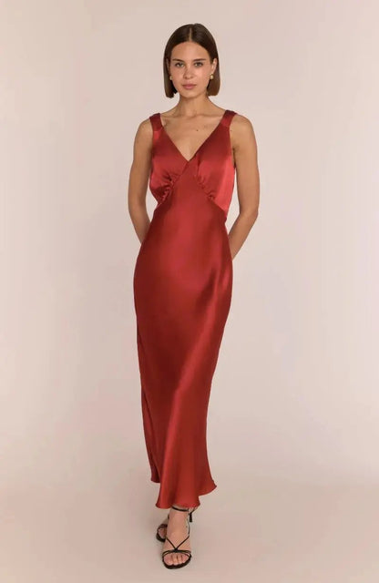 Woman wearing a red satin bridesmaid dress against a plain background