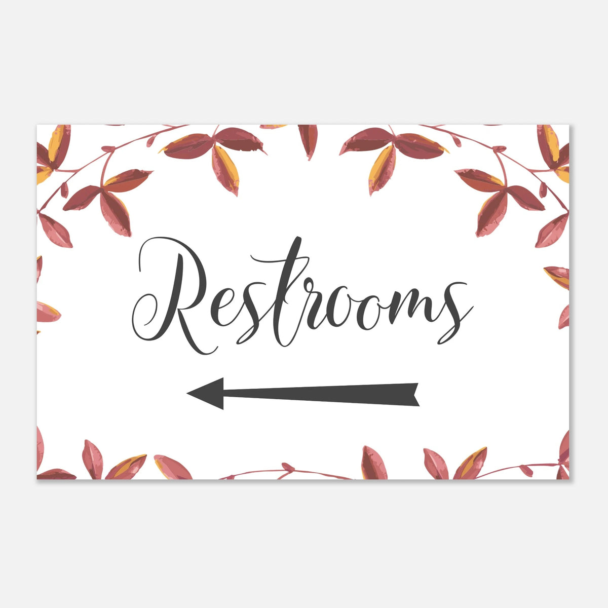 A rectangular restroom sign with a white background, black script reading 'Restrooms,' a black left-pointing arrow, and an autumn leaf border in muted red, brown, and yellow tones.