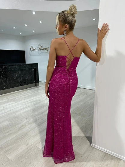 back view of girl wearing a dark fuchsia sequined thigh slit prom dress with spaghetti straps