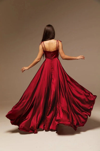 back view of girl wearing burgundy satin side slit backless prom dress with spaghetti straps