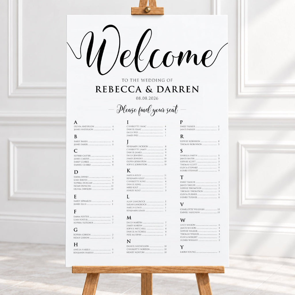 A wedding welcome sign printed on a white sheet, displayed on a wooden easel in a bright indoor setting with white paneled walls.