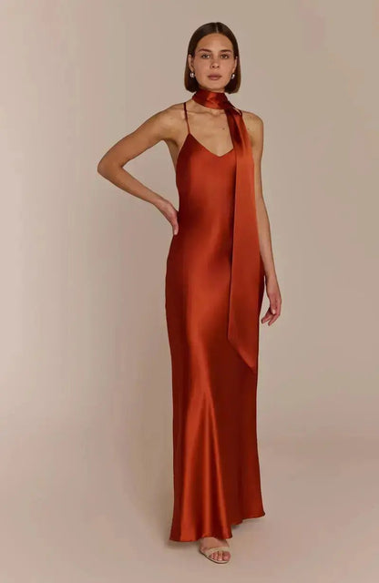 Woman wearing a rust-colored burnt orange satin bridesmaid dress against a beige background
