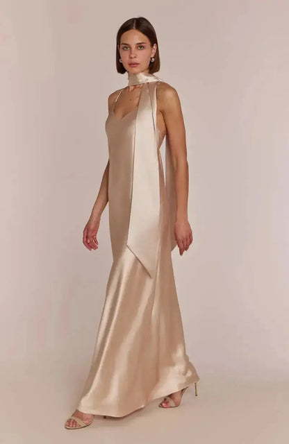 Woman wearing a champagne evening gown against a plain background