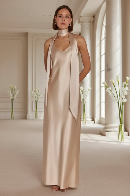 Bridesmaid wearing a champagne halter neck bridesmaid dress in a bright, elegant room at a fancy wedding venue with large windows.
