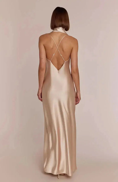 Woman wearing a champagne Bridesmaid  satin evening gown with a low back on a plain background