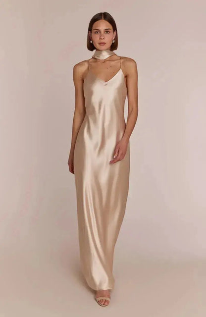 Bridesmaid wearing a champagne slip dress against a plain background