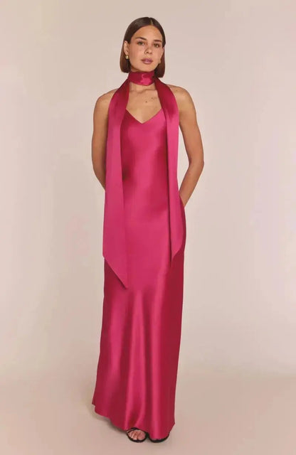 Bridesmaid wearing a long hot pink satin dress with a matching scarf on a beige background