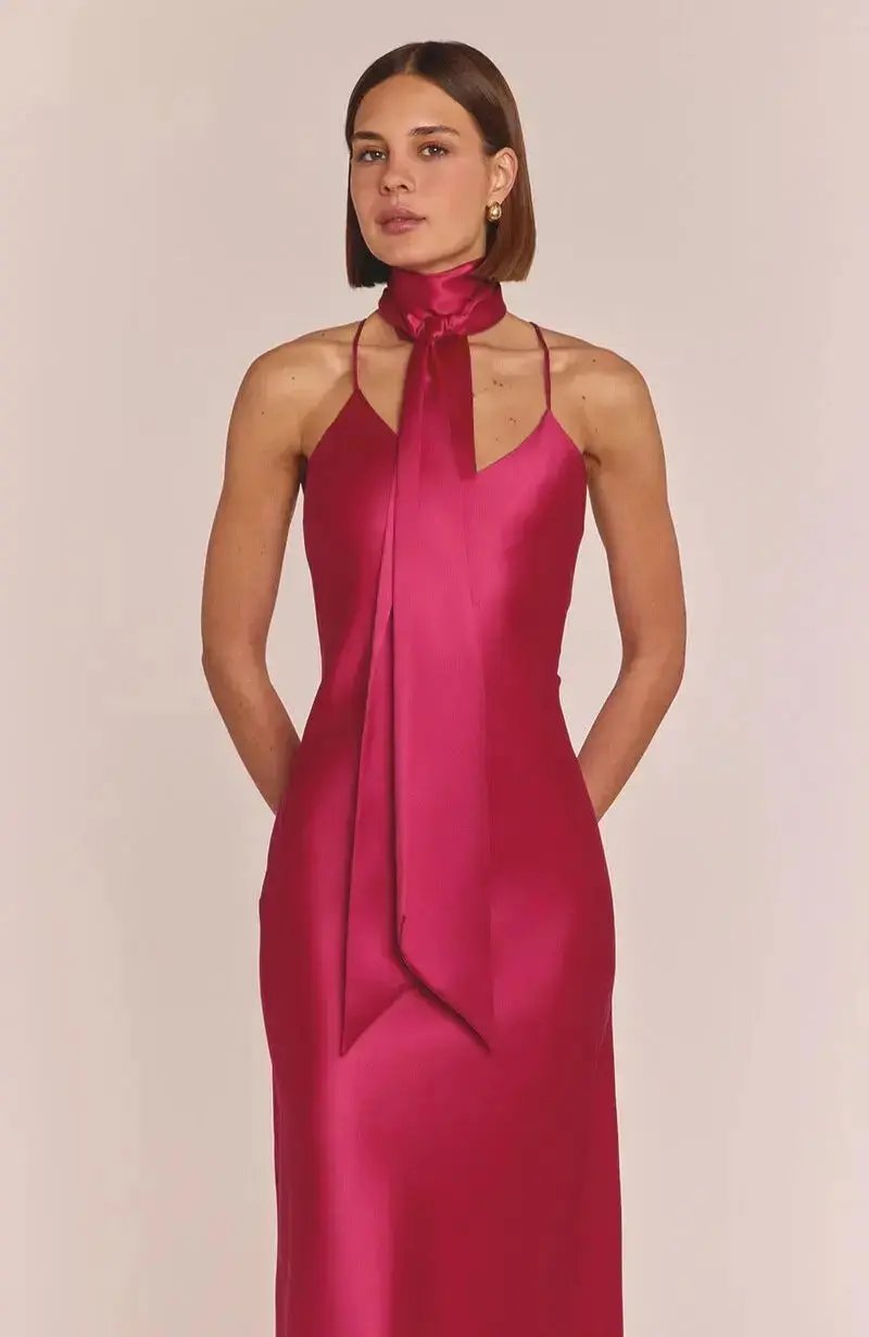 Woman wearing a pink halter neck dress against a plain background