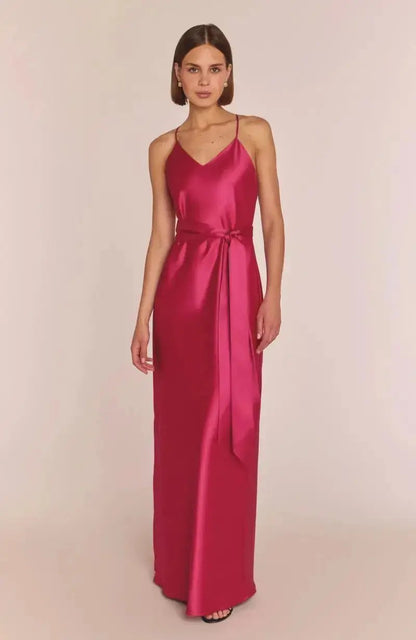 Woman wearing a pink satin gown against a plain background