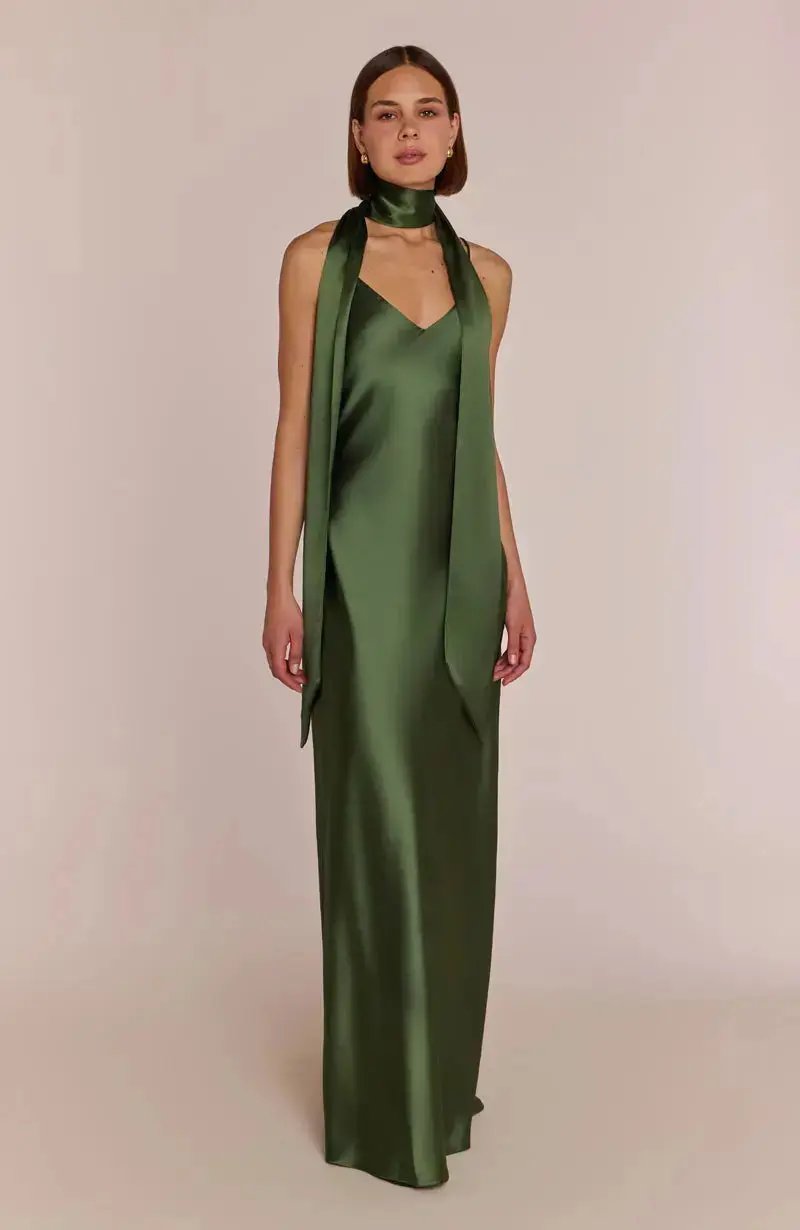 bridesmaid wearing a olive green satin dress with a matching scarf on a beige background