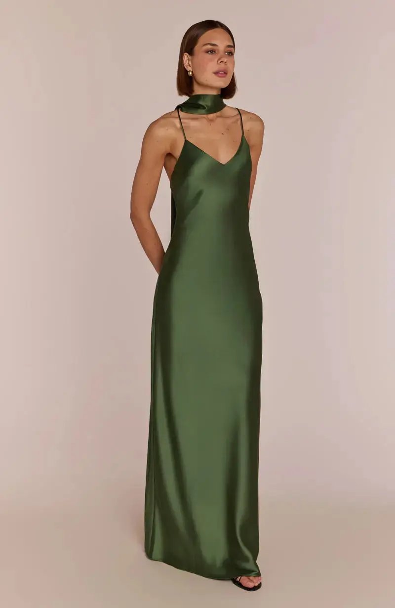 Woman wearing a olive green satin bridesmaid gown against a beige background