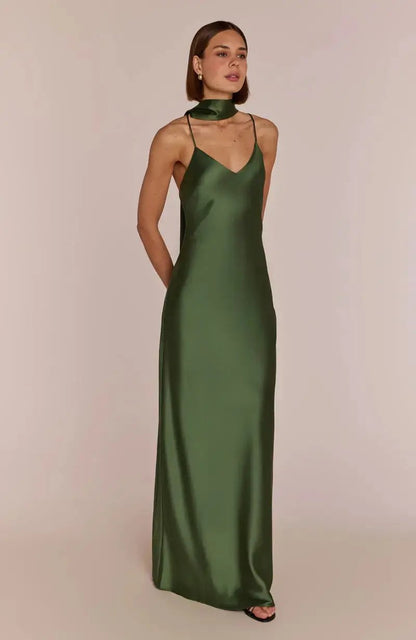 Woman wearing a olive green satin bridesmaid gown against a beige background