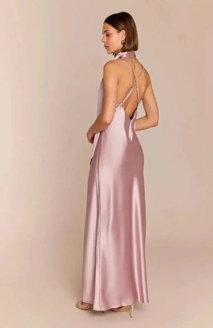 Woman wearing a pink satin bridesmaid gown with thin straps on a beige background
