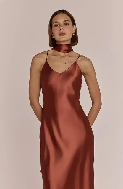 Bridesmaid wearing a rust-colored terracotta satin slip dress against a plain background