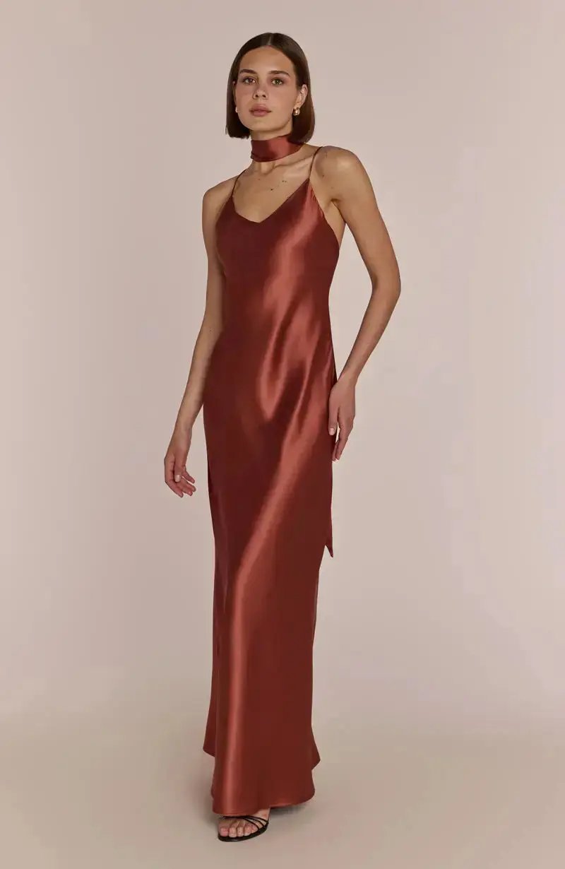 Bridesmaid wearing a terracotta brown bridesmaid satin dress against a beige background