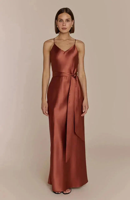 Woman wearing a satin terracotta brown bridesmaid gown against a beige background