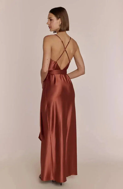 Woman wearing a satin terracotta brown bridesmaid dress with a backless design on a beige background
