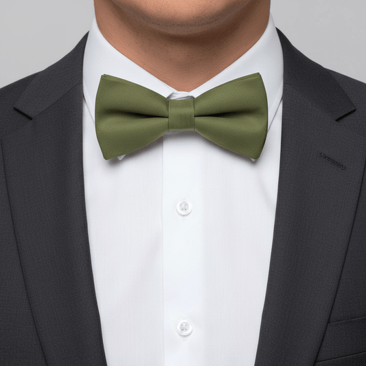 Green bow tie worn with a black suit and white shirt on a gray background