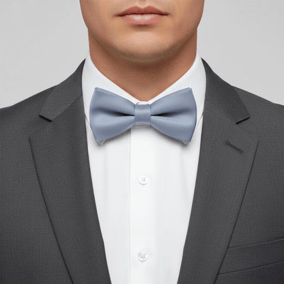 Man wearing a gray suit with a light blue bow tie on a plain background