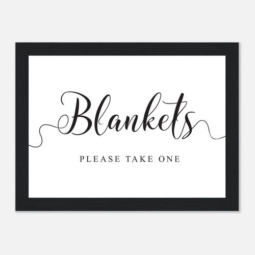 A framed sign with a black frame and a white background. The sign features the word 'Blankets' in large black script with decorative flourishes, and the text 'PLEASE TAKE ONE' printed below in a smaller serif font.