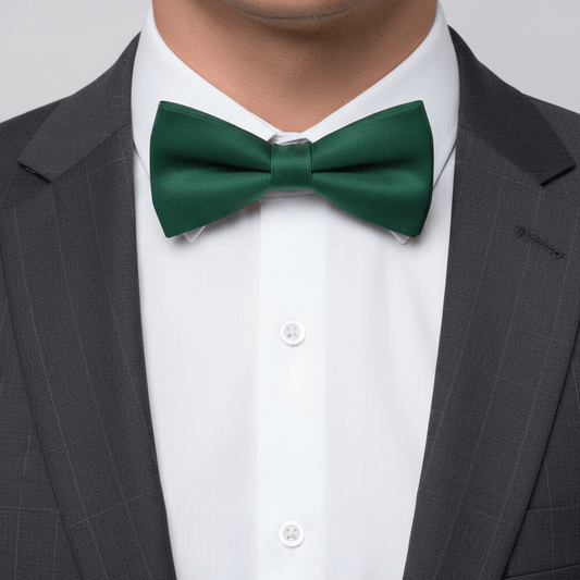 Green bow tie worn with a gray suit and white shirt on a plain background
