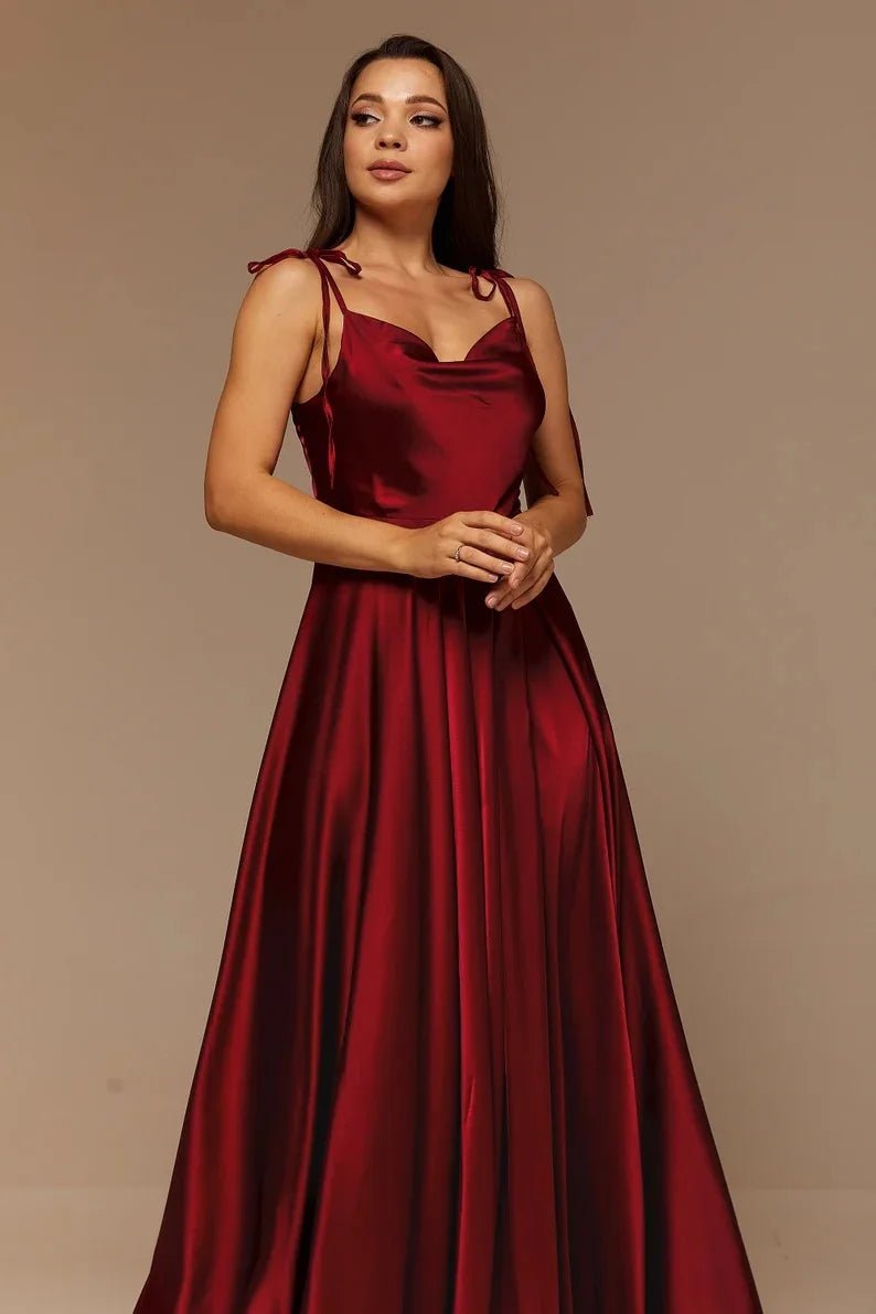 front side view of girl wearing burgundy satin side slit backless prom dress with spaghetti straps