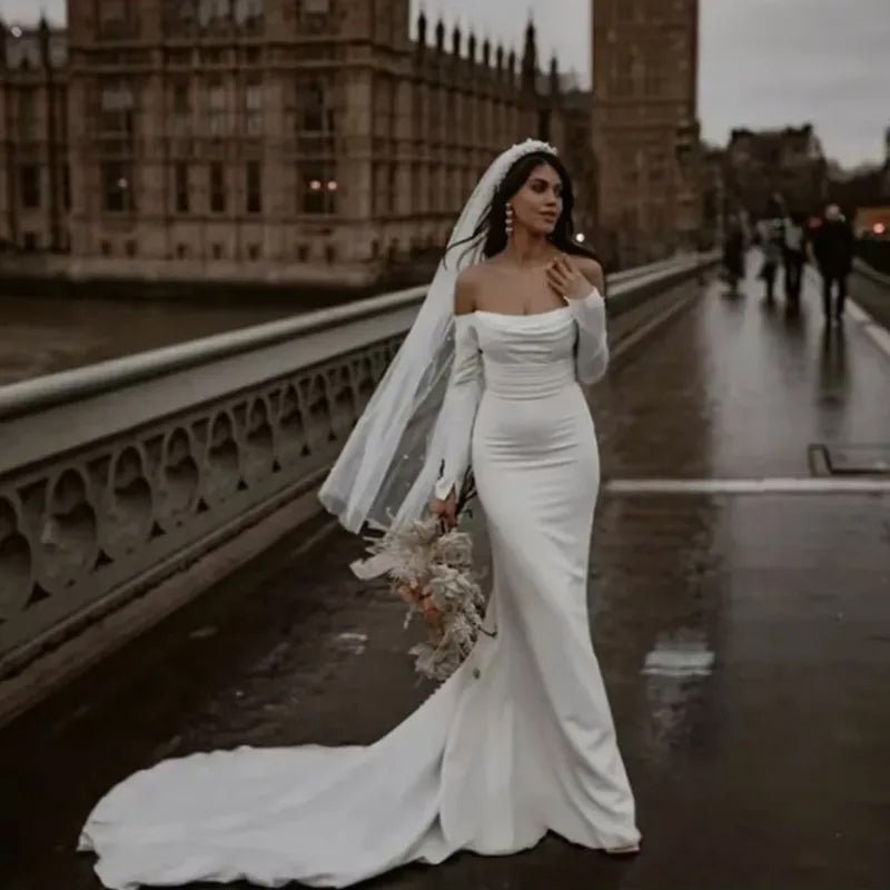 front view of bride on london bridge wearing a white Off-the-Shoulder Modern Satin Mermaid Wedding Dress with Long Sleeves